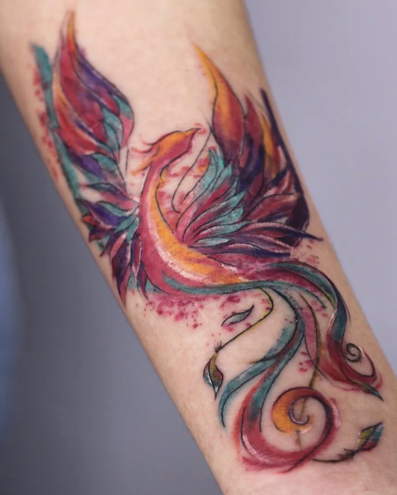 Fênix em aquarela laranja, vermelha e azul no antebraço