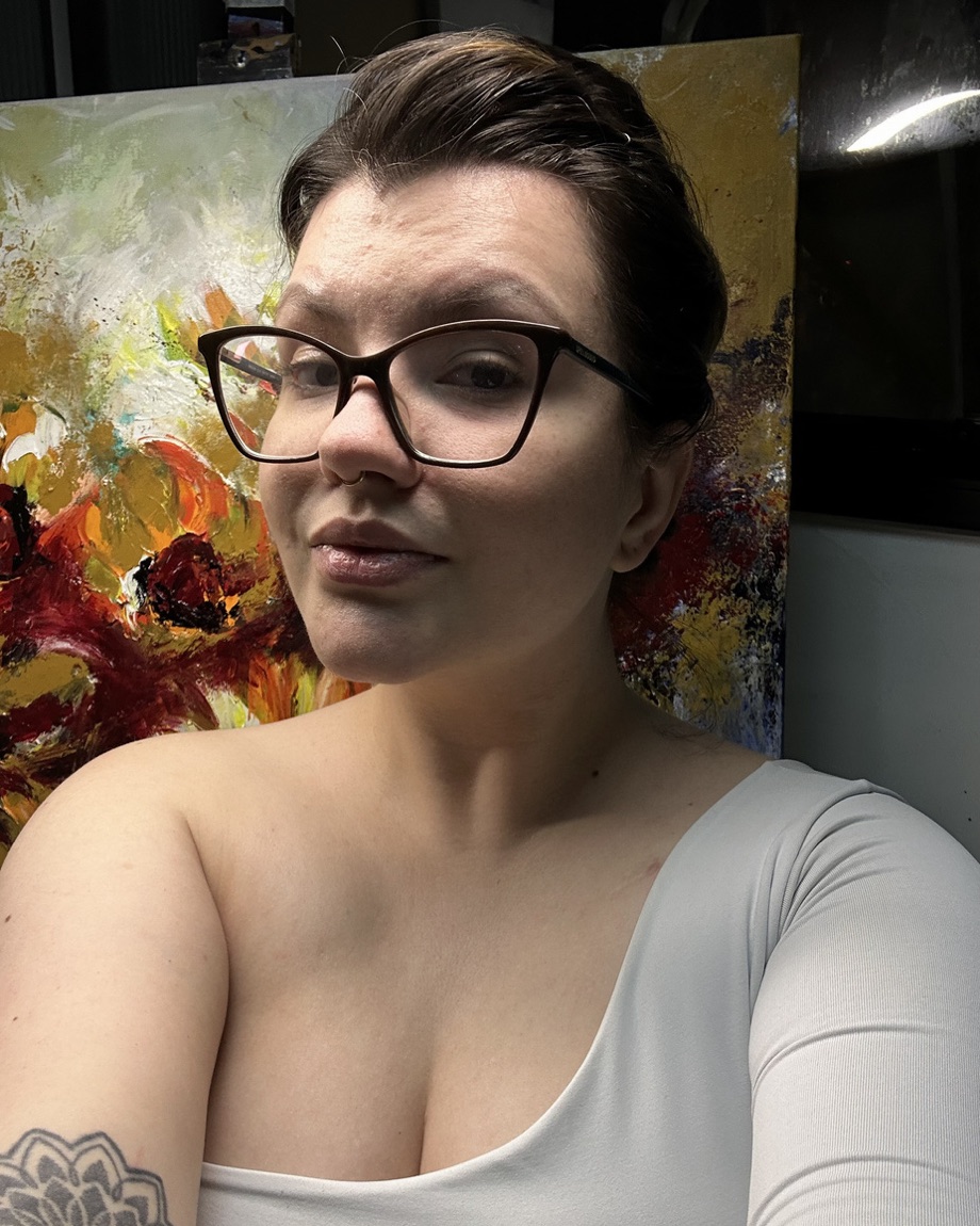 Yasmin Coiado no estúdio, diante de uma pintura abstrata